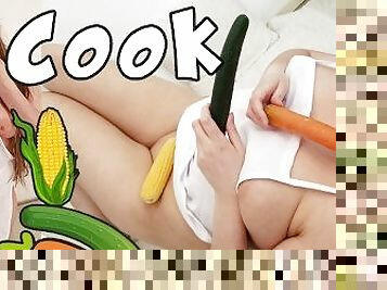 Chubby blonde cook inserting cucumber, carrot and corn