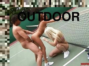 Threesome on a tennis court with a slim brunette and blonde American woman