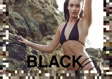 Breathtaking beauty in a black bikini playing on the beach